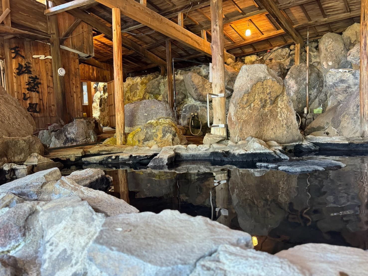 木の梁と大きな岩を取り込んだ旅の湯の浴場
